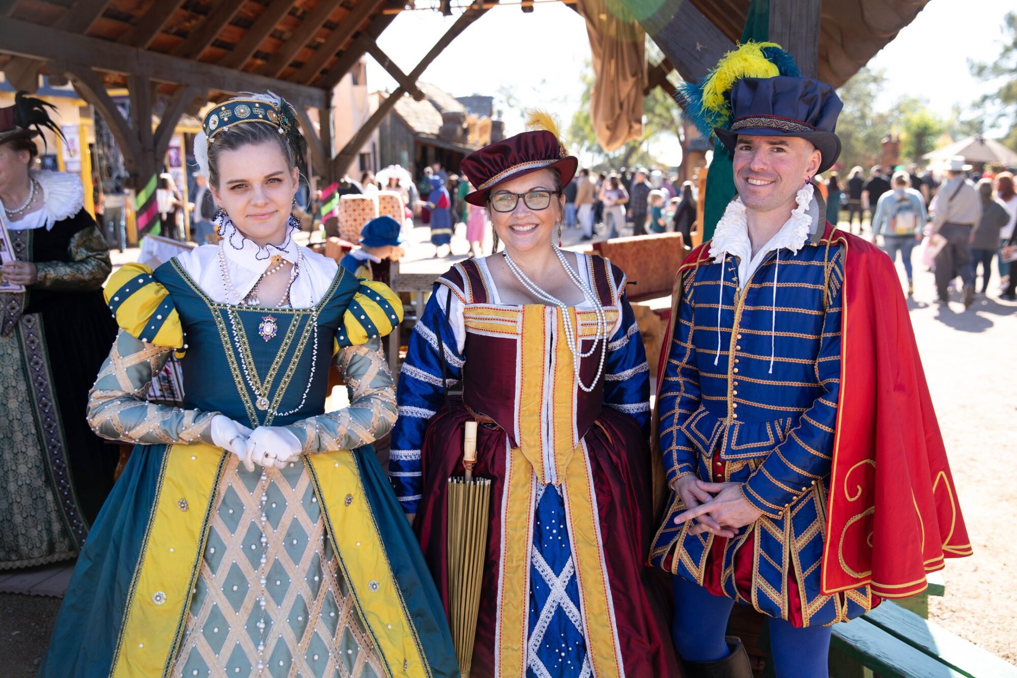 Three people are wearing renaissance costumes. There are two young women and one man.